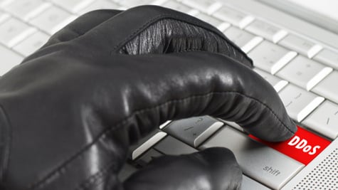 Gloved hand clicking DDoS button on keyboard