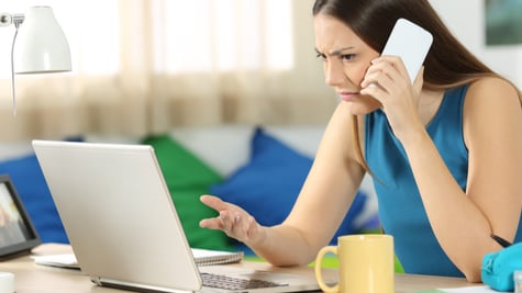 Angry person looking at computer and talking on the phone