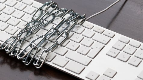 Keyboard wrapped in chain. Vigilante cybercrime concept