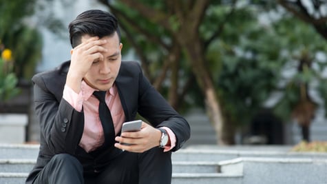 Man looking at mobile phone with serious face, negative emotion, phishing scams concept.