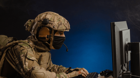 Soldier in full combat gear sat at computer