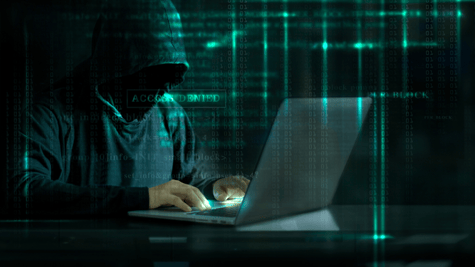 Hooded person using laptop in a matrix background