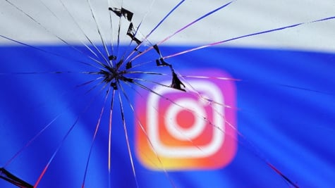 Russian flag and Instagram logo are seen through broken glas