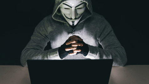 Anonymous masked guy in front of laptop folding hands