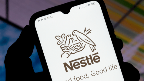 Shadowy hand holding mobile phone with Nestle logo displayed