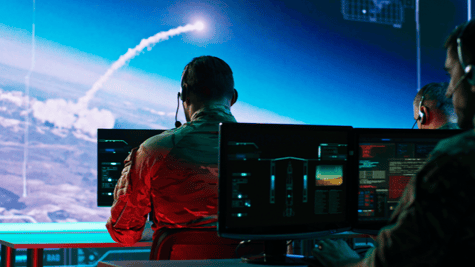 Rear shot of military personnel in bunker overseeing missile warfare