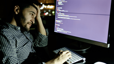 Tried worker in front of computer screen looking at data