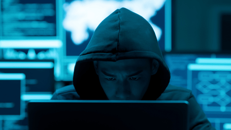 Asian man looking intently at a laptop, face partly concealed