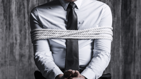 Man in suit and tie, tied to a chair. No head shot.