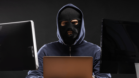 Man in balaclava with computer