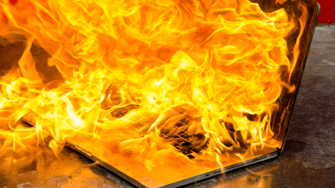 Laptop soaked in gasoline/petrol burning, metaphorical image for wiper malware that destroys data.