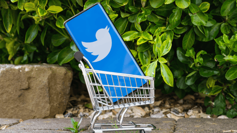 Smartphone with Twitter logo placed in a miniature shopping cart