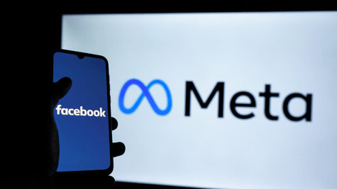 Mobile phone with Meta on it and Facebook branding in background