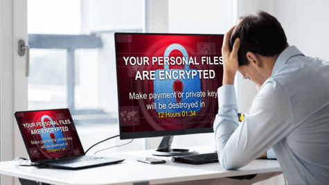 Office worker in despair in front of encrypted computer.