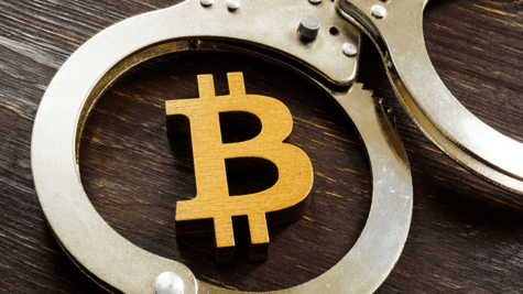 Handcuffs around a bitcoin in symbolic image.