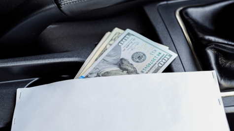 Gearstick inside car with envelope stuffed with cash