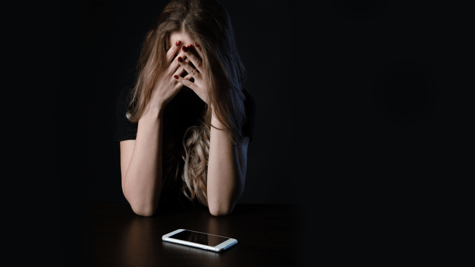 Woman holding head in hands with cellphone
