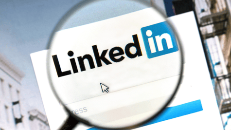 Magnifiying glass over LinkedIn logo on computer screen