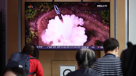 People watch a TV broadcasting a news report on North Korea firing a space satellite.