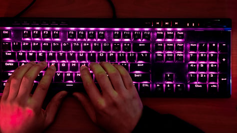 Hands of a glowing mechanical keyboard, typing
