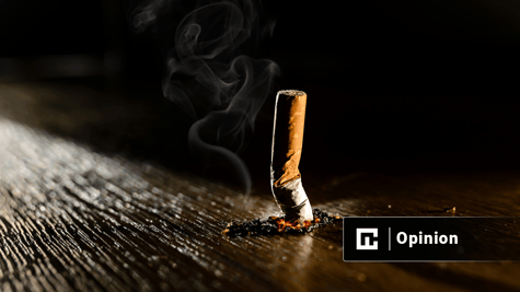 A smoking burning cigarette on a dark floor background.