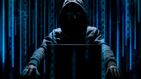 Shadowy hacker with binary screen in background