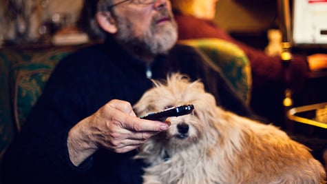 Man watching TV with dog on lap