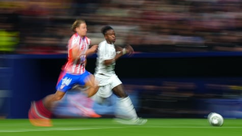 Two footballers chasing the ball in the Madrid derby.