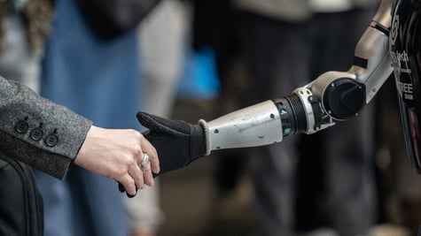 Human person shaking hands with Unitree humanoid robot