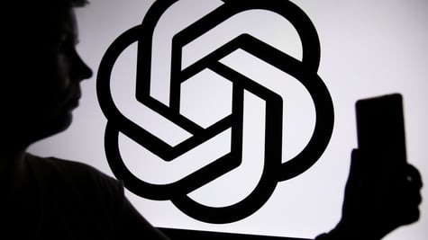 Someone talking a selfie next to the OpenAI logo in silhouette form.
