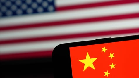 Chinese flag on phone in forefront, US flag in background