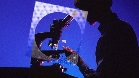 A scientist looking at an intercrystal under a microscope