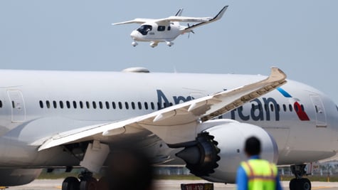two white aircrafts with blurry staff in front, blue sky
