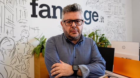 italian man with glasses and dark blue shirt with arms crossed and glasses, grey hair