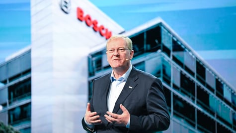 Stefan Hartung in suit and blue shirt, glasses, glass building