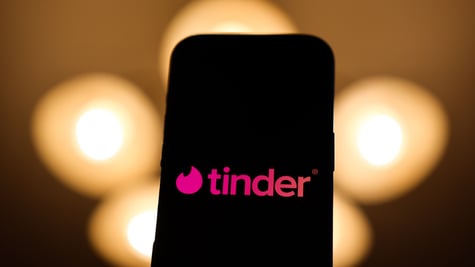 tinder logo in black screen on phone in romantic warm background
