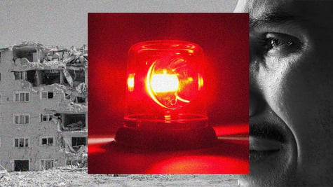 A red siren, mounted on top of an affected victim of an earthquake, and damaged building.
