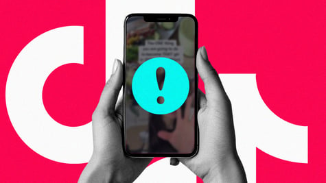 A pair of hands holding a cell phone with the TikTok logo and an exclamation mark.
