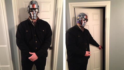 man in black jeans jacket, silver mask, opens white doors, blocks doors