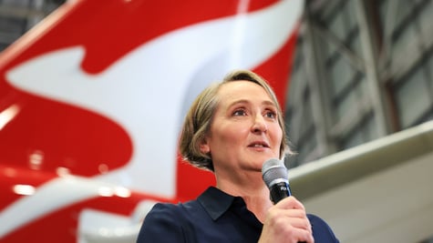 Qantas CEO Vanessa Hudson speaking to a microphone next to a plane