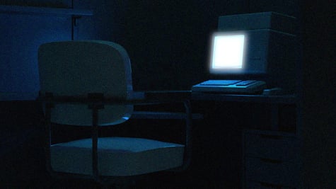 An empty chair in front of a desk with a laptop