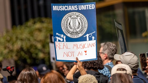 Protestors hold a poster saying "Real musicians not AI"