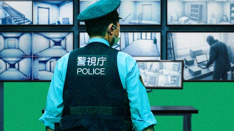 A Tokyo cop watching AI surveillance screens.