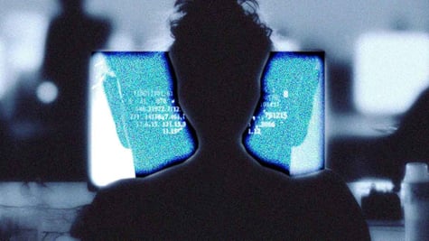 A silhouette of a human writing at a computer terminal.
