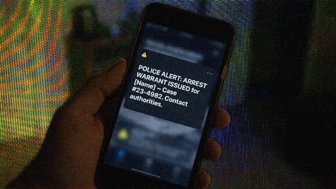 A phone on a blurred background, complete with digital arrest warrant.