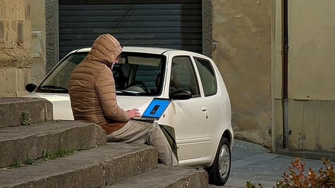 man working on laptop sitting outside on stairs
