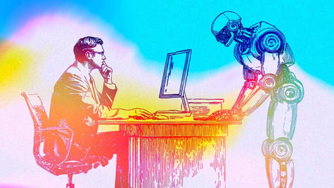 A person sitting at the desk looking at the computer screen and a robot working