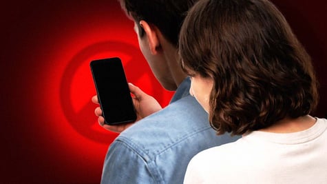 Person looking over shoulder at a smartphone with black screen