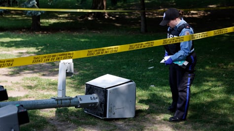 A broken camera with police standing over it.