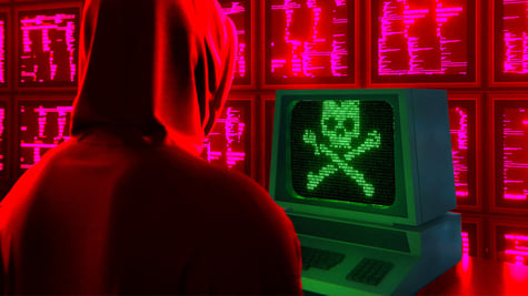 Hacker facing screen with scull; cyber threat